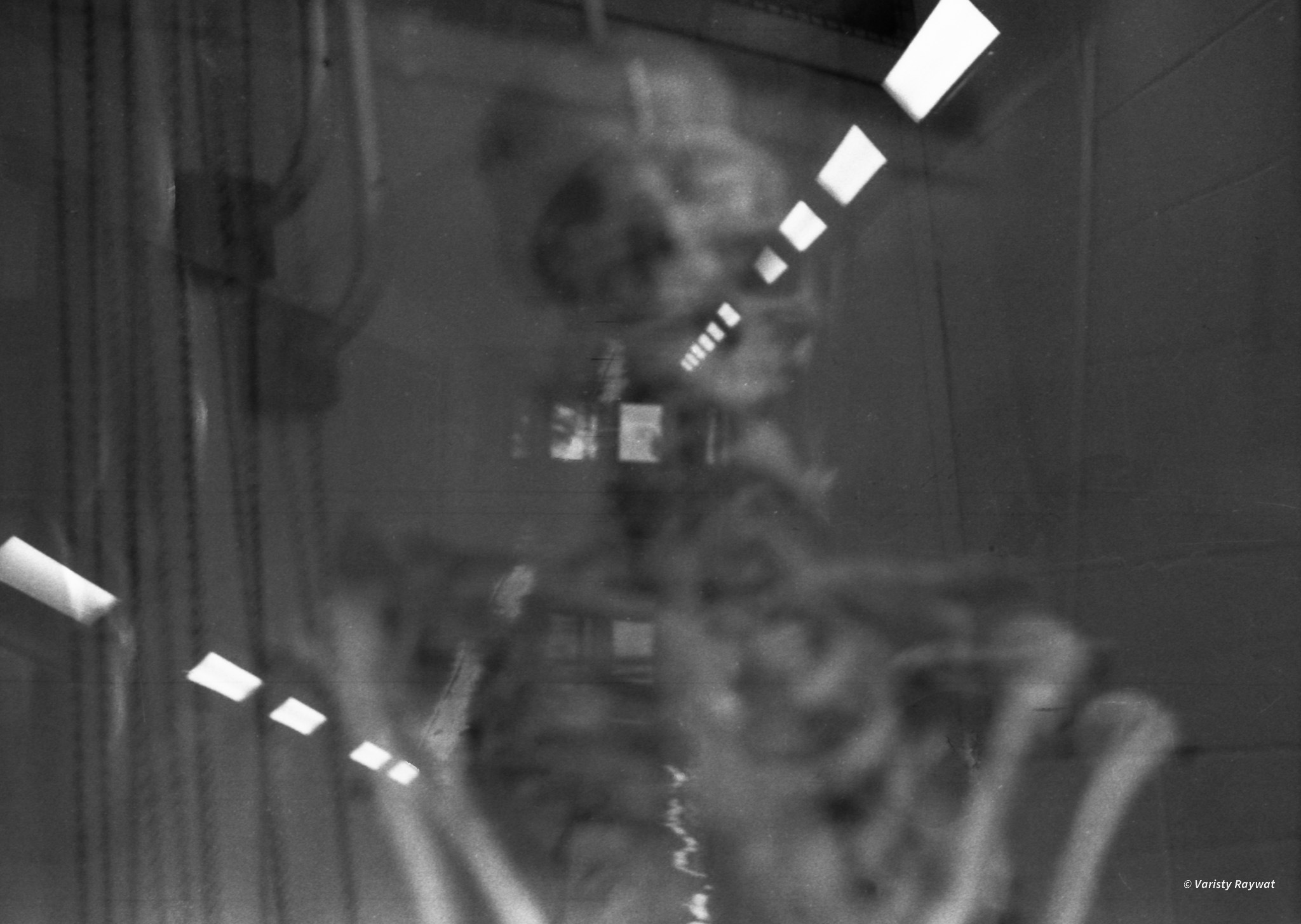 A skeleton reflected in glass against the lights of a corridor
